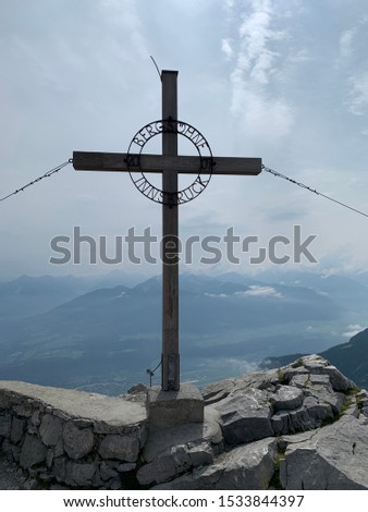 Cross located on top of the Hafelekarspitze and in the background the views of the city of Innsbruck in Austria