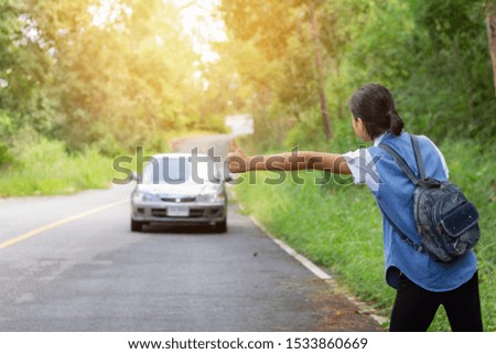 young girl with backpack hitchhiking hand sign on the road,stop concept,