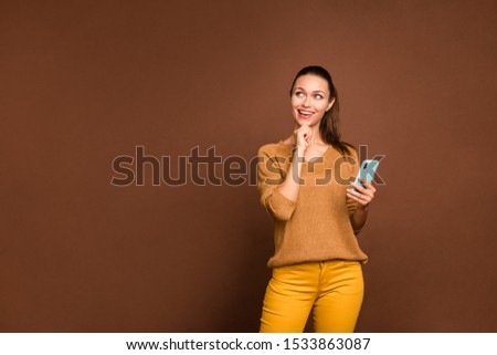 Photo of cheerful nice cute dreamy girl pensively looking up at empty space pondering over answering received message isolated over brown pastel color background