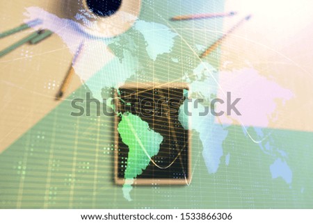 Double exposure of world map drawing on digital tablet laying on table background. Concept of international trade
