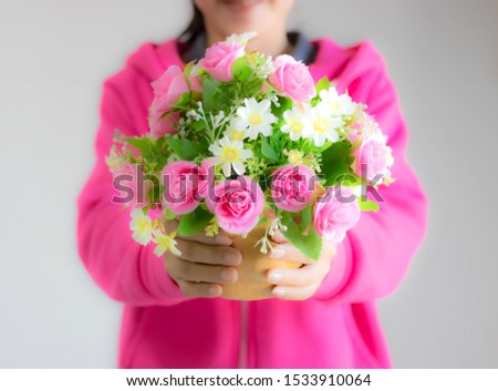 Girl wearing pink blurred image holding a bouquet of colorful flowers deliver to lover. Giving good feelings to each other pink flowers represent love and care. White represents purity.