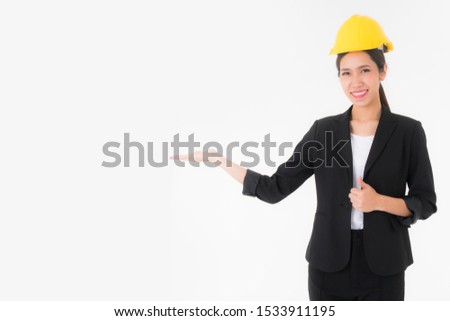 Smiling Asian young engineer woman wearing black suit  and Yellow Safety helmet stand and showing something or presenting a copy space isolated on white background studio portrait