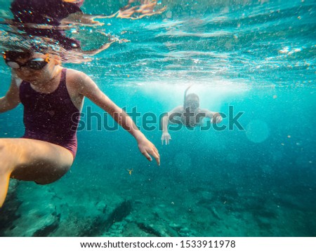 Father and daughter snorkeling in the clear deep blue sea
