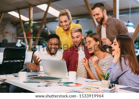 Lucky corporate team. Designers celebrate successful project realization, looking at laptop Royalty-Free Stock Photo #1533919964