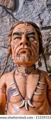 Old carved cigar store Indian - stone wall as background