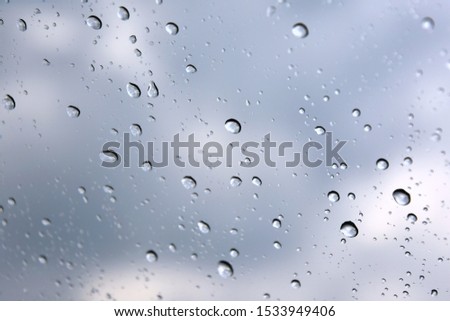 Rain drops with selective focus on transparent glass. Glass surface with water drops, violet toned. Window with raindrops. water drops on glass