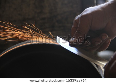 Sparks grinding wheel while knife sharpening Royalty-Free Stock Photo #1533955964