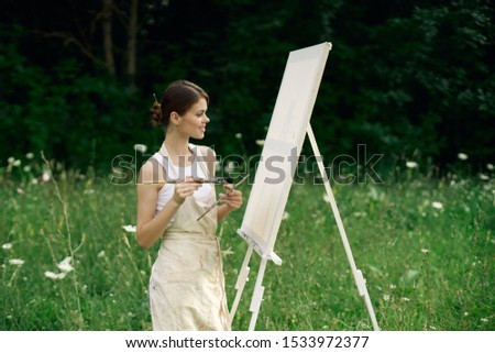woman beautiful model easel paints a picture