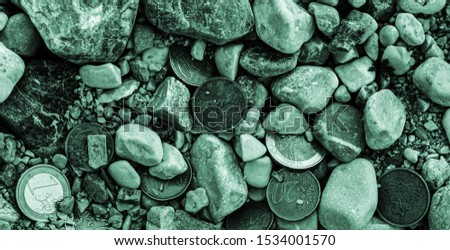 dramatic cold image of euro coins heap on the ground amid stones high angle view close up