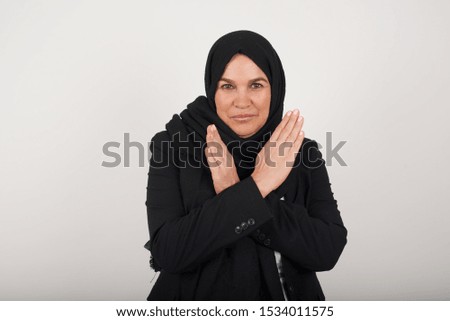 Young beautiful muslim woman standing over isolated background. Has rejection angry expression crossing hands doing refusal negative sign.