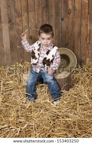 little cowboy in a barn with straw