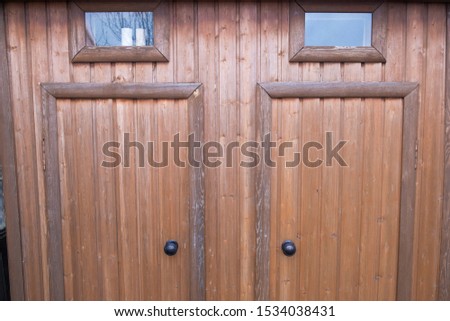 New Toilet and shower made of wood closeup. Garden plot. Glass small Windows. Two wooden doors. Country plot.