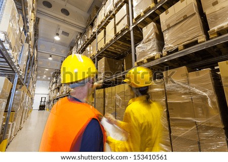 Two managers checking products in huge warehouse