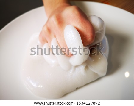 Hands and fingers playing with creamy white ivory pearl slime