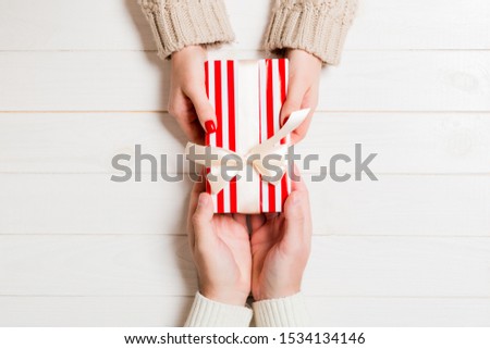 Top view of giving and receiving a gift on wooden background. Present in male and female hands. Love concept. Close up.