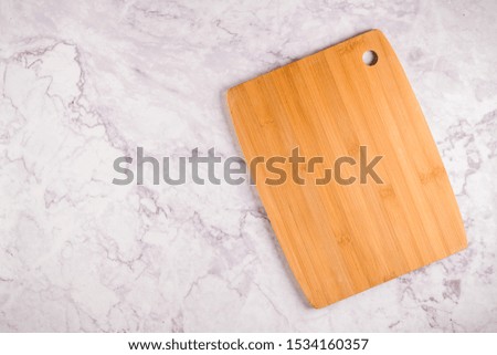 Top view of wooden cutting board on a gray marble background with space for text.