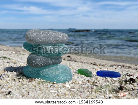 Seaglass stack on beach sand with seascape background. Beachcombing, beach walk. Harmony and balance concept. Royalty-Free Stock Photo #1534169540