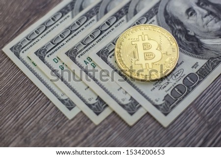 Bitcoin coin lies on dollar bills. The concept of internet currency as a competitor to paper money.