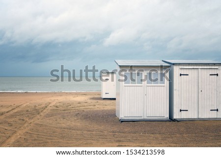 A beautiful shot of white small rooms on a beach shore near the water under a cloudy sky