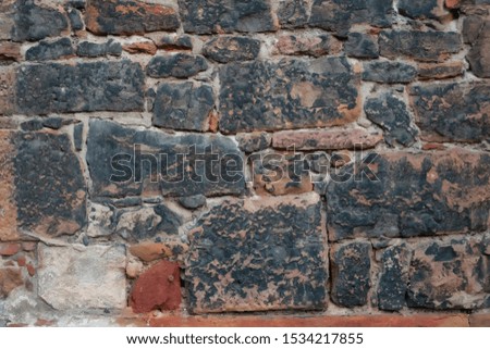Fragment of an old wall of stones blackened by time. Background. Texture.
