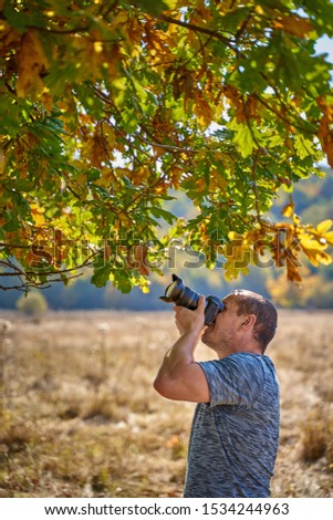Professional nature photographer taking photos in the forest in an autumn day