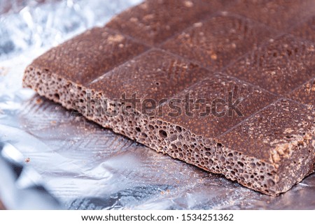 porous milk dark chocolate lies on the foil. close-up. A popular dessert.