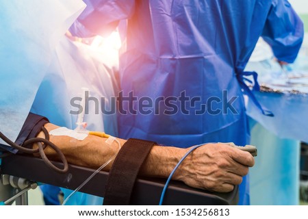 Restrainted patient on the operation table in surgery with a drip in a hand. Patient's hand with a sensor,Hand critically ill patients. IV fluids. Closeup. Royalty-Free Stock Photo #1534256813