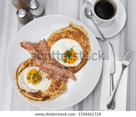 Breakfast with bacon, eggs, pancakes and coffee on white marble table