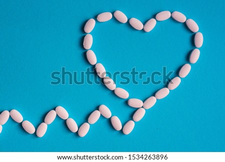 White medical pills in shape of heart on blue background.  Royalty-Free Stock Photo #1534263896