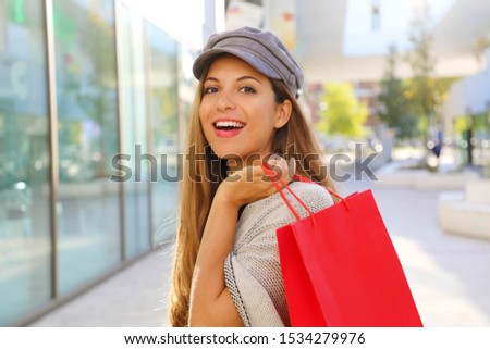Black Friday. Happy smiling fashion woman holding shopping bag in her hand looks at camera in a shopping mall.