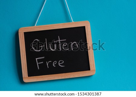 Black chalk board with 'Gluten Free' message written on it, against blue background  Royalty-Free Stock Photo #1534301387