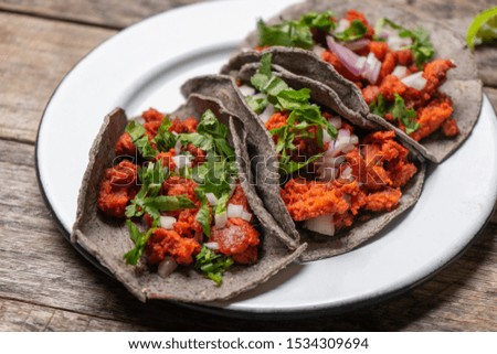 Traditional mexican chorizo tacos with blue corn tortillas on wooden background