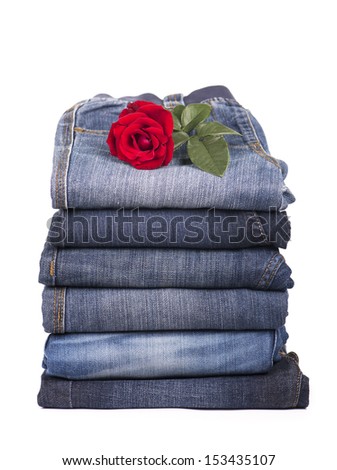 jeans clothes are put by a pile and a red rose on a white background 