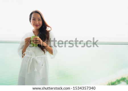 Beautiful Portrait young asian women holding coffee cup at outdoor balcony with sea ocean view for relax