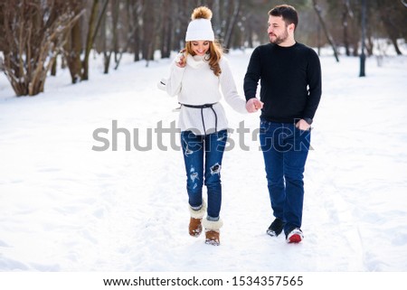 Loving couple walking on a date in a winter Park. On the girl's back hanging a pair of skates.