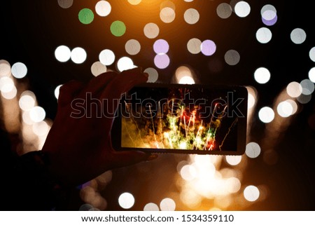 Hand of man taking the photo of fireworks by smartphone.
