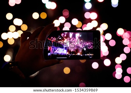 Hand of man taking the photo of fireworks by smartphone.