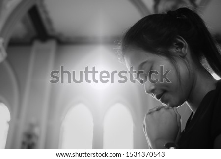 A beautiful Asian woman is praying to God with His blessing for a better life in a Christian church in Chanthaburi province. The concept of forgiveness and belief in goodness.Monochrome picture.
