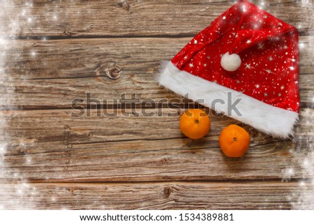 Wooden background with mandarines and Christmas hat on the table. Winter holiday frame. Flat lay top view. copy space