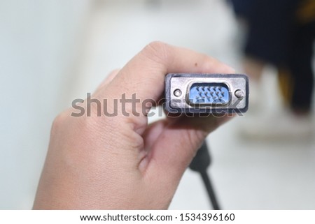 Eternal projector screen connector hold by left hand with blurred background of classroom
