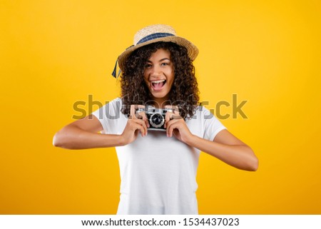 trendy hipster black girl with vintage camera and hat isolated over yellow