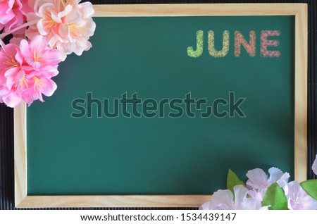 June month write with colorful chalk, flowers on the board.