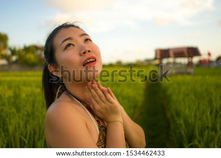 young happy and beautiful Asian woman enjoying nature at rice field. sweet Chinese girl in Summer dress at green field exploring countryside during holiday travel in wanderlust and tourism