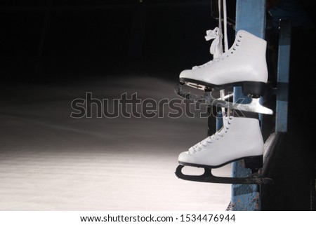 white ice skates hanging on ice rink