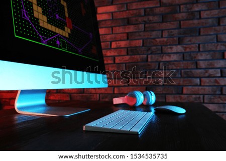 Modern computer and headphones on table in dark room. Playing video games