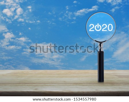 2020 start up flat icon with magnifying glass on wooden table over blue sky with white clouds, Business happy new year 2020 concept