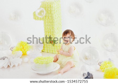 a little girl eats cake with her hands on the bacfground of fireplace. The baby was covered in food. birthday party