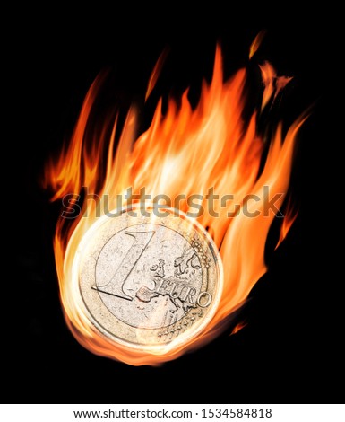 Burning one euro coin in flames on the black background. Conceptual photo.