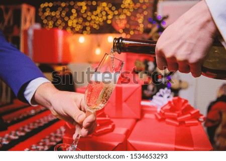 Celebrate new year with champagne. Cheers concept. Hands pouring champagne into elegant glass christmas decorations background. Last minute before new year. Drink champagne or sparkling wine.
