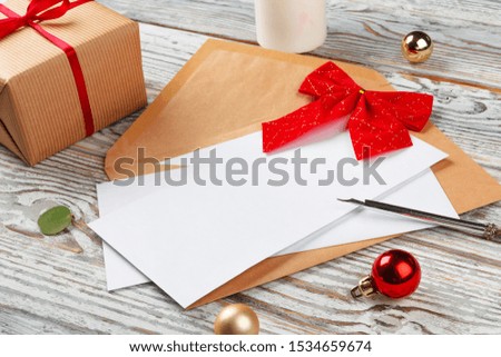 Close up of Christmas letter writing on yellow paper on wooden background with decorations
